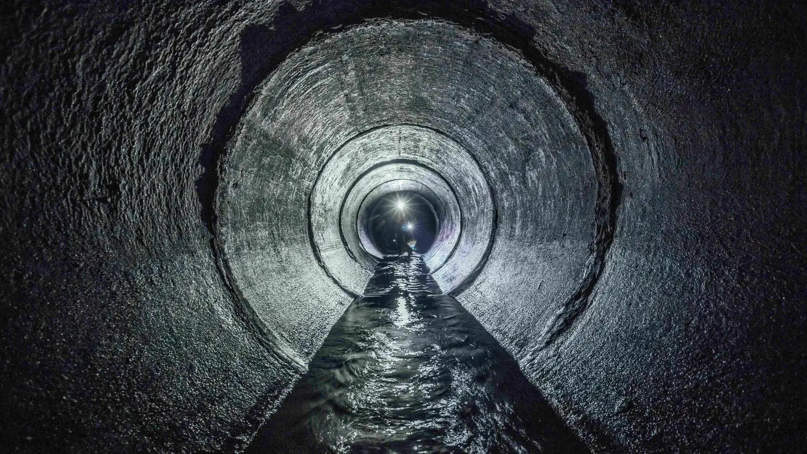 Inside a concrete sewer pipe with water flowing through it