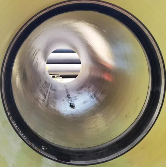 Field engineer inspecting a concrete pipe joint for groundwater infiltration and void formation.